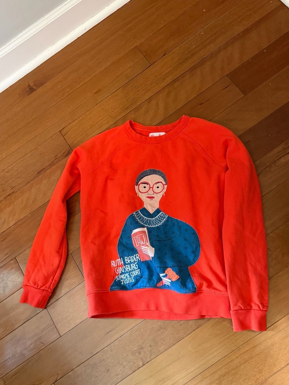 Piccolina 
red sweatshirt an embroidered graphic of Ruth Bader Ginsburg